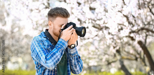 Handsome male photographer with modern camera outdoors