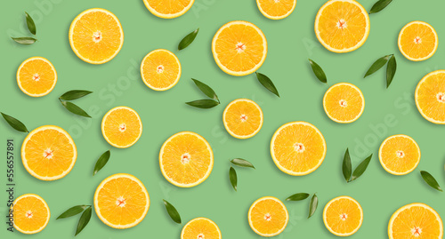 Pieces of fresh oranges with green leaves on green background. Pattern for design