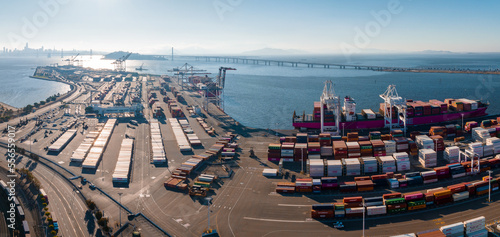 The Oakland Outer Harbor aerial view. Loaded trucks moving by Container cranes. View of busy Port of Oakland. Shipping terminal facility.