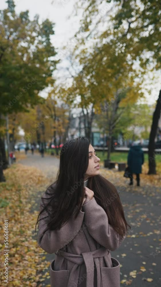 Woman in an autumn coat tries to keep warm on the street Woman in an autumn coat tries to keep warm on the street