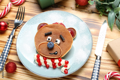 Plate with bear made of pancakes, fruits and Christmas decor on wooden table, closeup