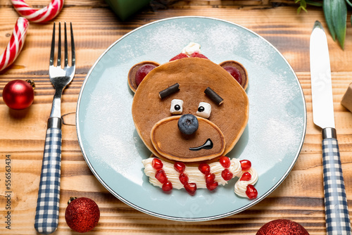 Plate with bear made of pancakes, fruits and Christmas decor on wooden table, closeup