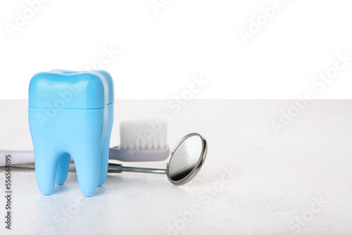 Plastic tooth with brush and dental tool on table against white background