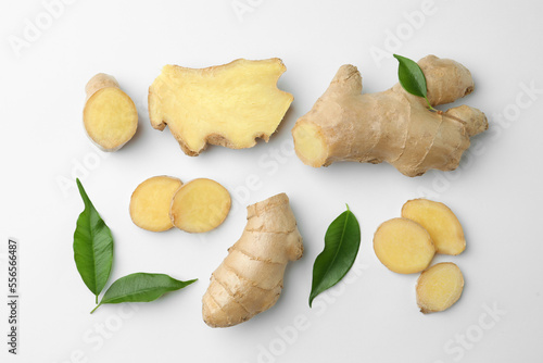Fresh ginger with green leaves on white background, flat lay