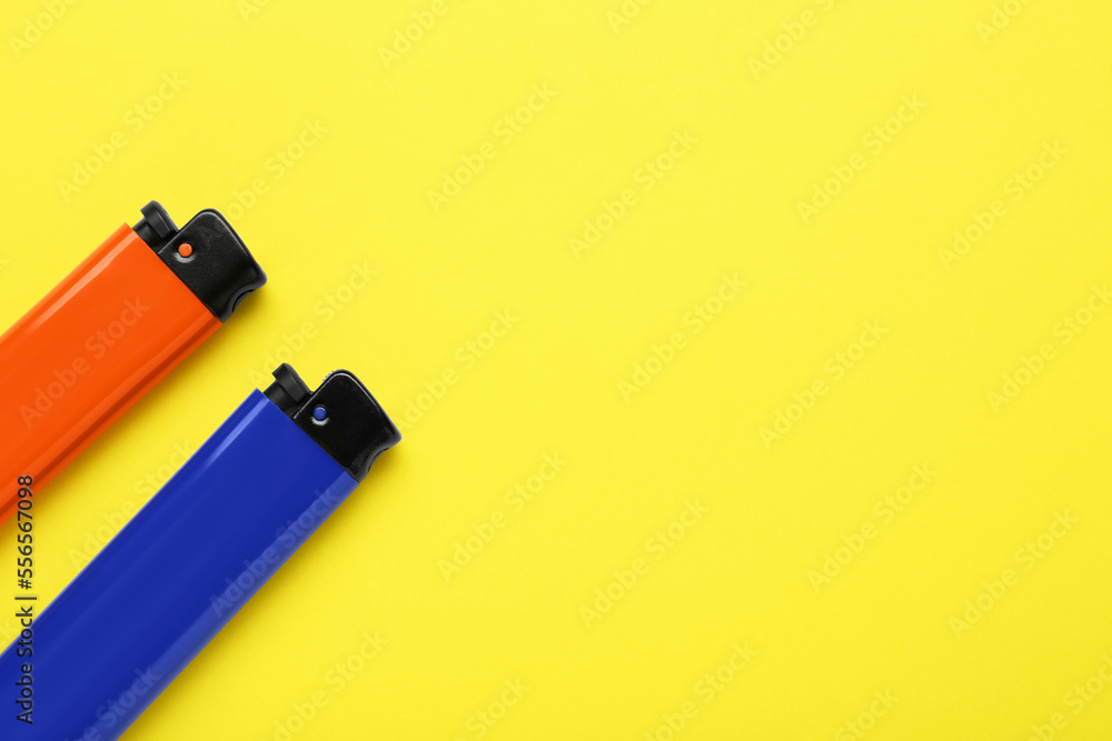 Stylish small pocket lighters on yellow background, flat lay. Space for text Stylish small pocket lighters on yellow background, flat lay. Space for text