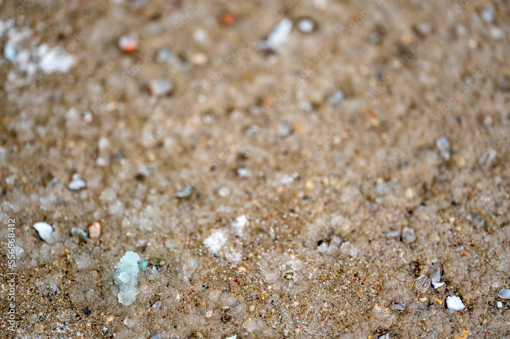macro ground level closeup view of rock salt ice-melt on concrete with a frozen layer. macro ground level closeup view of rock salt ice-melt on concrete with a frozen layer.