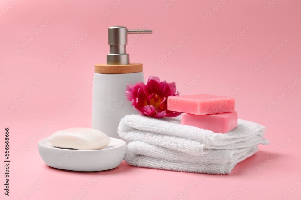 Soap bars, bottle dispenser and towels on pink background Soap bars, bottle dispenser and towels on pink background