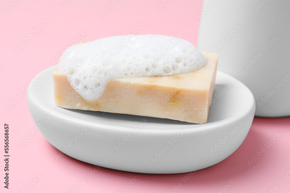 Dish with soap bar and fluffy foam on pink background, closeup Dish with soap bar and fluffy foam on pink background, closeup