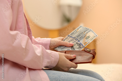 Woman counting dollar bills indoors, closeup. Money exchange