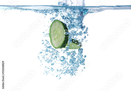 Slices of fresh cucumber falling into water on white background, closeup
