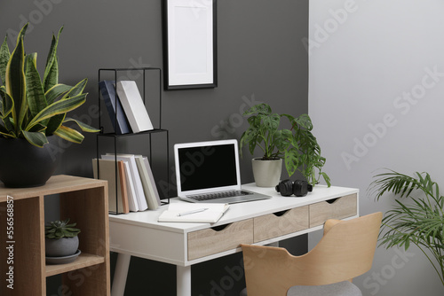 Workplace with laptop, stationery on desk and chair in home office © New Africa
