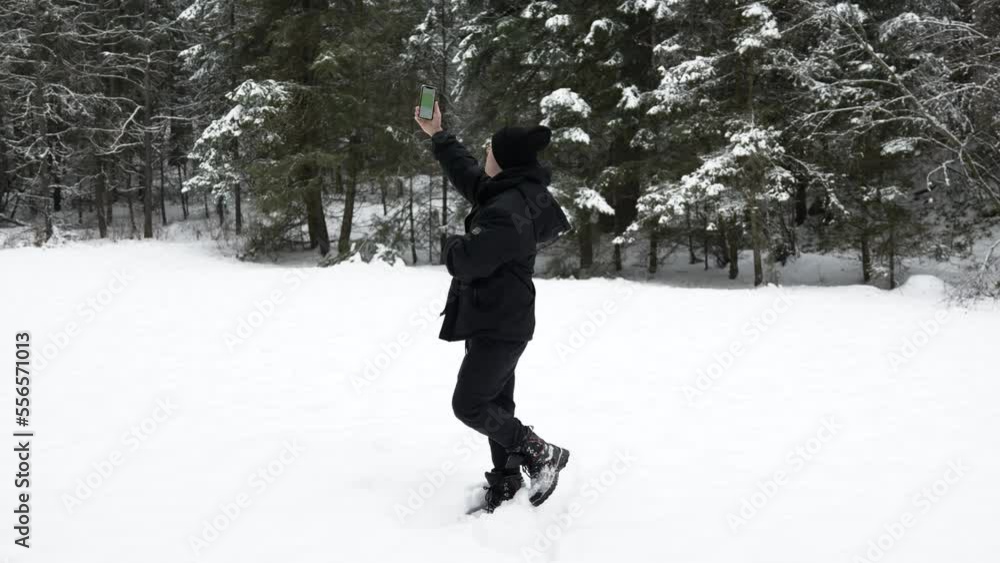 Young adult male trying to get cell service in a snowy winter tree forest Young adult male trying to get cell service in a snowy winter tree forest