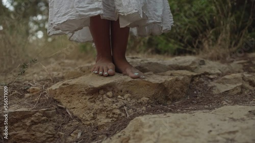 A woman in white dress is walking barefood in the forrest photo