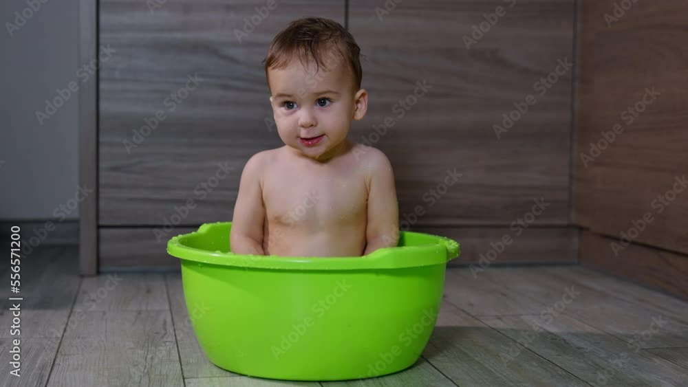 Little pretty Caucasian baby boy sits calmly in the tub. Nice child looks curiously around ready to be washed. Little pretty Caucasian baby boy sits calmly in the tub. Nice child looks curiously around ready to be washed.