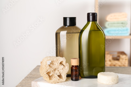 Solid shampoo bar and bottles of cosmetic product on wooden table in bathroom, space for text