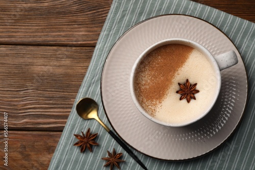 Cup of delicious eggnog with anise on wooden table, top view. Space for tex
