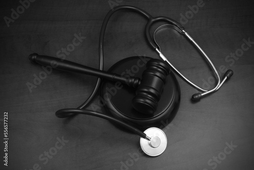 Wooden judge gavel and stethoscope on table. Malpractice and crimes concept.