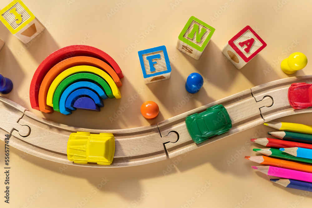 Wooden railway, blocks, rainbow, cars  on beige background. Preschool, elementary school education. Development games for kids. Educational daycare toys.