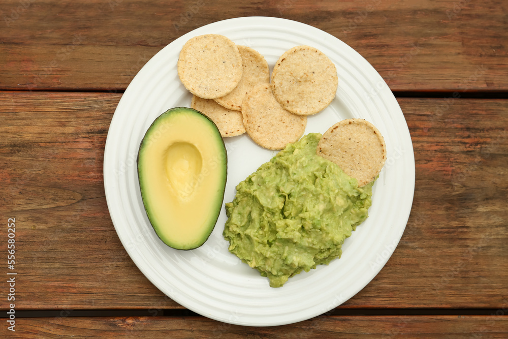 Delicious guacamole, avocado and chips on wooden table, top view Delicious guacamole, avocado and chips on wooden table, top view