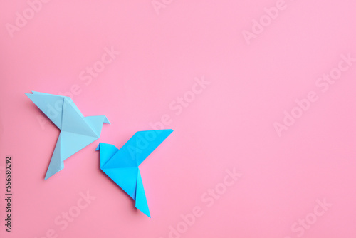 Beautiful light blue origami birds on pink background, flat lay. Space for text