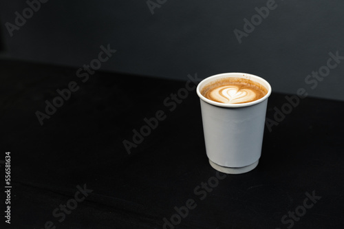 latte coffee on a paper cup served on white table at cafe​