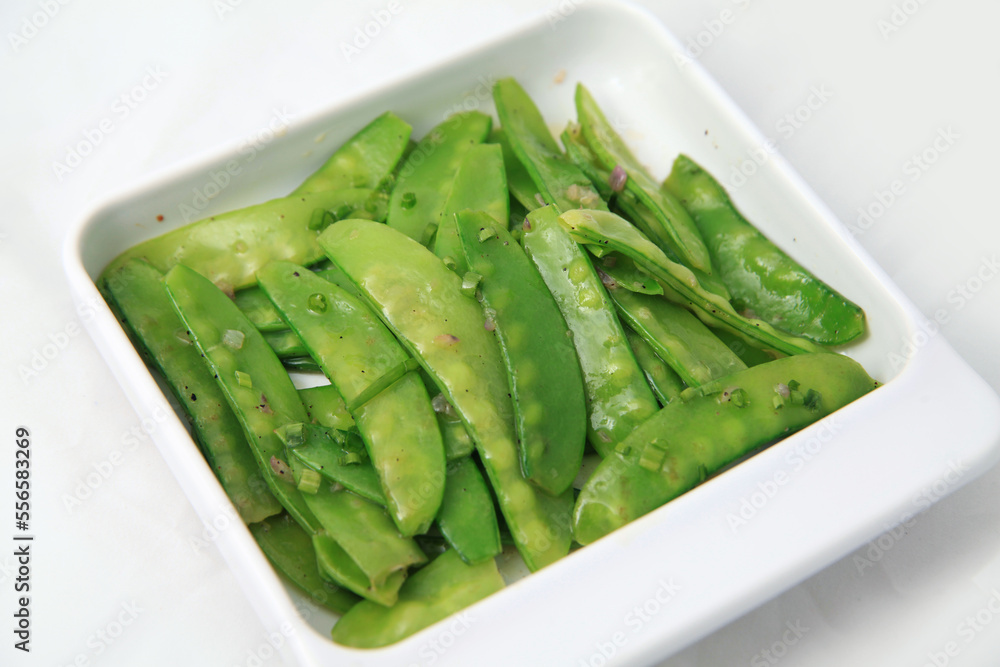 healthy organic stir fried snow peas in square rectangular white plate, vegetarian food, peas with edible pea pods healthy organic stir fried snow peas in square rectangular white plate, vegetarian food, peas with edible pea pods