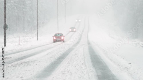 Cars drive in bad driving weather in winter in the snow