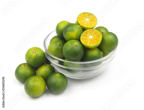 Fresh calamansi lime fruits in glass bowl isolated on white background.	