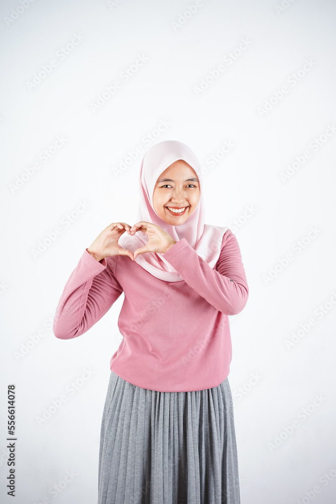 Beautiful Asian woman in pink sweater and hijab feeling happy and romantic shape heart gesture expressing tender feelings on white background Beautiful Asian woman in pink sweater and hijab feeling happy and romantic shape heart gesture expressing tender feelings on white background