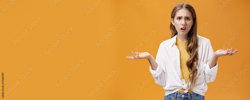 What, I do not understand. Portrait of arrogant questioned impolite girl being pissed with questiones shrugging with hands spread sideways making irritated grimace standing confused over orange wall - obrazy, fototapety, plakaty 