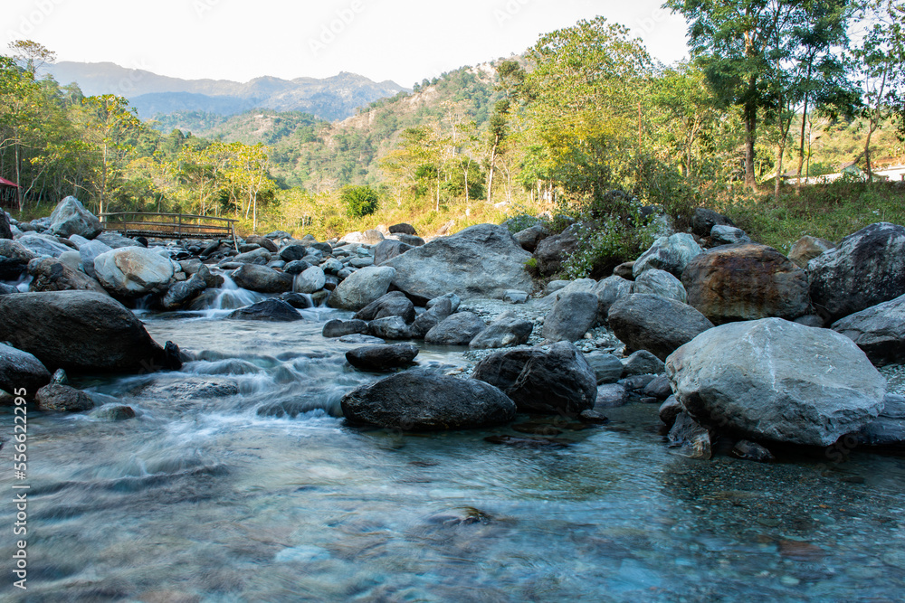 Long exposure milky effect of a beautiful landscape of mountain river coming through rocks and a wooden bridge over the river. Long exposure milky effect of a beautiful landscape of mountain river coming through rocks and a wooden bridge over the river.