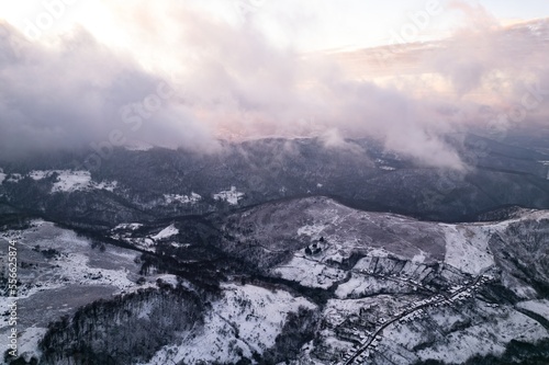 Aerial view of a village covered in snow, in a mountainous rural area, from Romania. Captured with a drone, in winter conditions. 