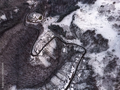 Aerial view of a village covered in snow, in a mountainous rural area, from Romania. Captured with a drone, in winter conditions.
