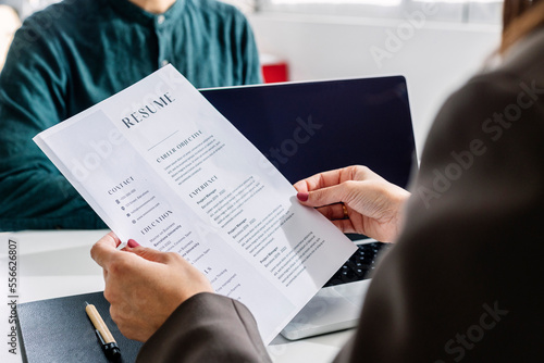 Hands of recruiter holding resume in front of candidate at desk photo
