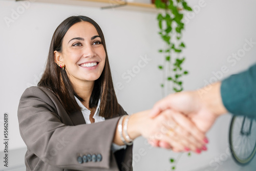 Happy recruiter shaking hand with candidate in office