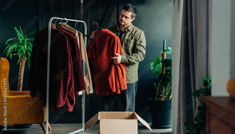 Man holding shirt standing by rack at home Man holding shirt standing by rack at home