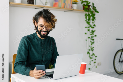 Smiling businessman using mobile phone at desk