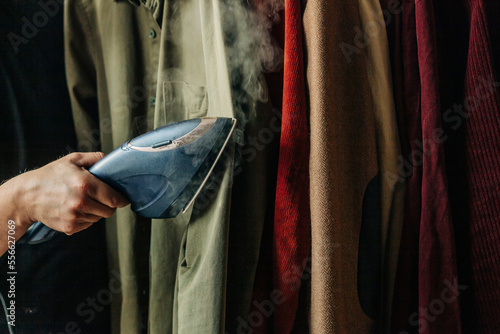 Hand of man steam ironing clothes photo