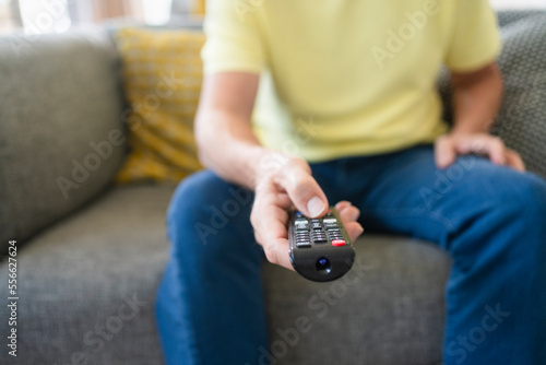 Hand of man holding remote control on sofa