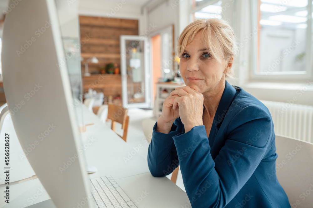 Mature businesswoman in front of desktop PC at office desk Mature businesswoman in front of desktop PC at office desk