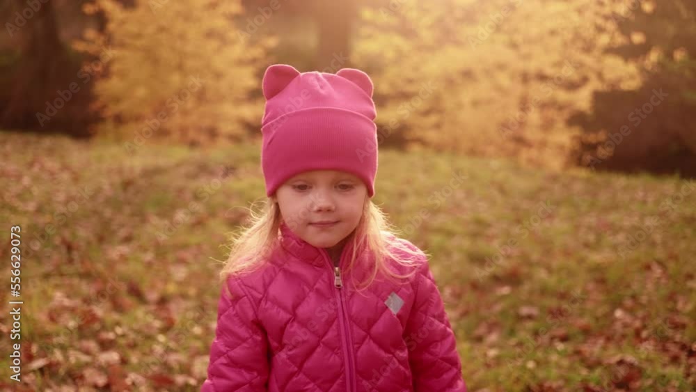Portrait of sinister little girl planning a murder, then starting to smile, red and yellow leaves background. Cute child wearing pink outfit, autumn park. Freaky kid's reaction to filming . HQ 4k Portrait of sinister little girl planning a murder, then starting to smile, red and yellow leaves background. Cute child wearing pink outfit, autumn park. Freaky kid's reaction to filming . HQ 4k