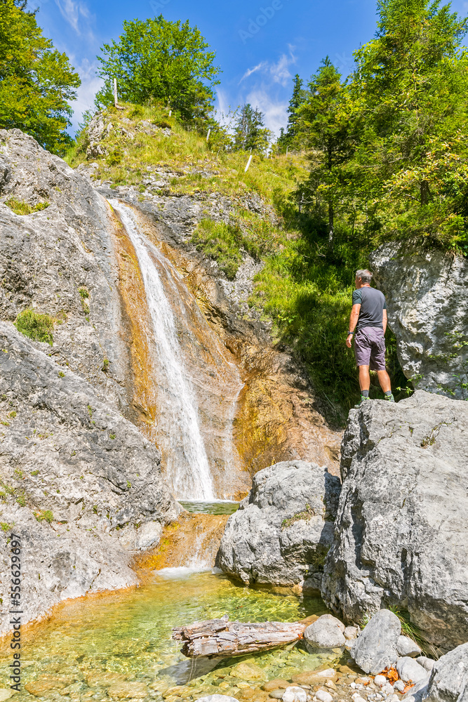 Germany, Bavaria, Male tourist standing on top of boulder lying in front ofRappinbachwaterfall Germany, Bavaria, Male tourist standing on top of boulder lying in front ofRappinbachwaterfall