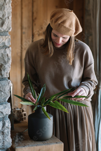 Woman with barret arranging twigs in flower vase photo