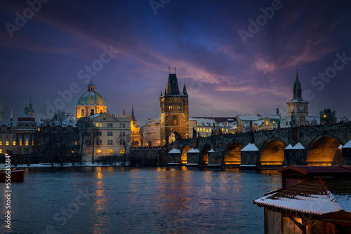Beautiful winter evening view of the illuminated skyline of Prague with Charles Bridge and the snow covered old town roofs, Czezch Republic  photo
