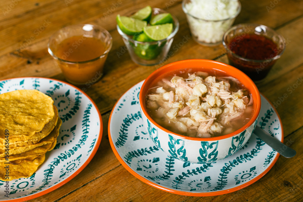 Pozole served in a deep dish, with tostadas, salsa and vegetables on a wooden table. Typical Mexican food. Pozole served in a deep dish, with tostadas, salsa and vegetables on a wooden table. Typical Mexican food.