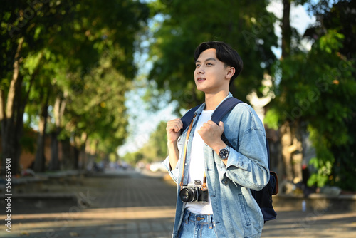 Handsome man in hipster outfit spending free time outdoors, walking in the city park on beautiful day © Prathankarnpap