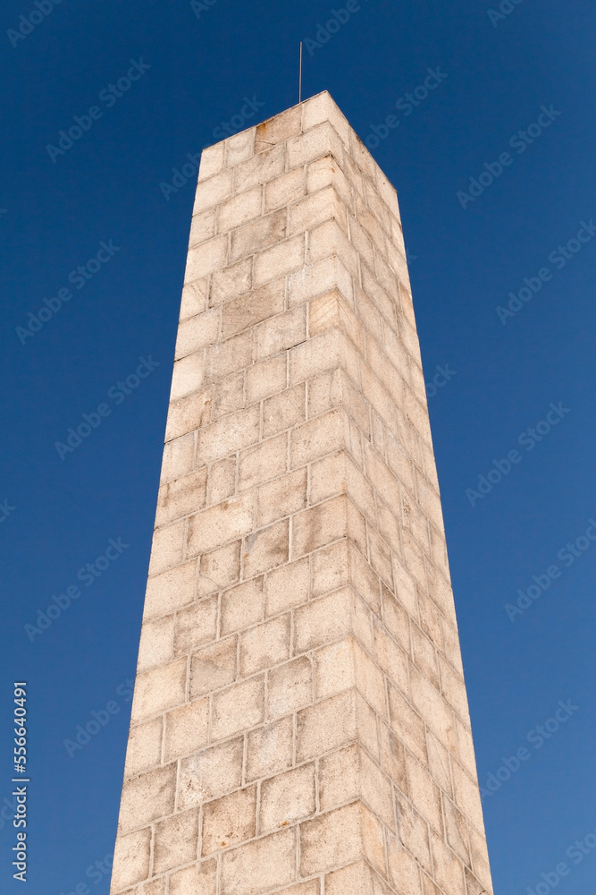 Stone obelisk is under blue sky. Obelisk of Fiolent Memory park