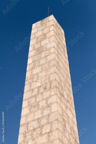 Stone obelisk is under blue sky. Obelisk of Fiolent Memory park