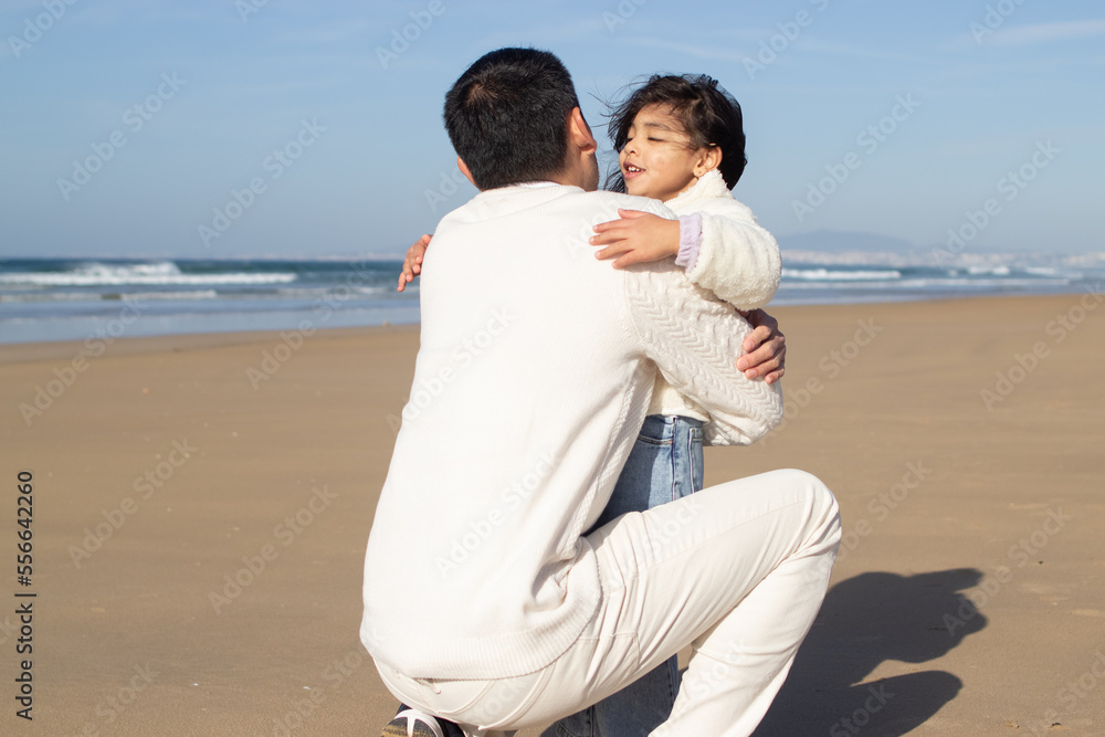 Tender father and daughter playing on beach. Japanese family on sunny day, hugging. Dad leisure, family time, parenting concept