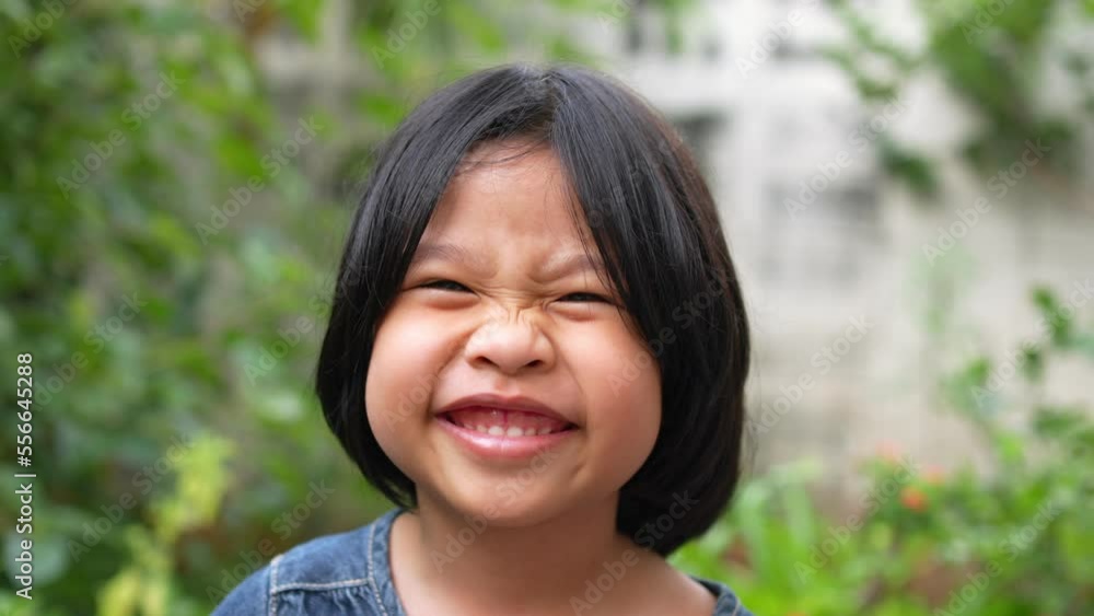 Portrait Funny little asian girl big smiling child looking at camera and pointing her cheeks, enjoying childhood testimonial concept, Positive child, 4k footage, Slow Motion Portrait Portrait Funny little asian girl big smiling child looking at camera and pointing her cheeks, enjoying childhood testimonial concept, Positive child, 4k footage, Slow Motion Portrait